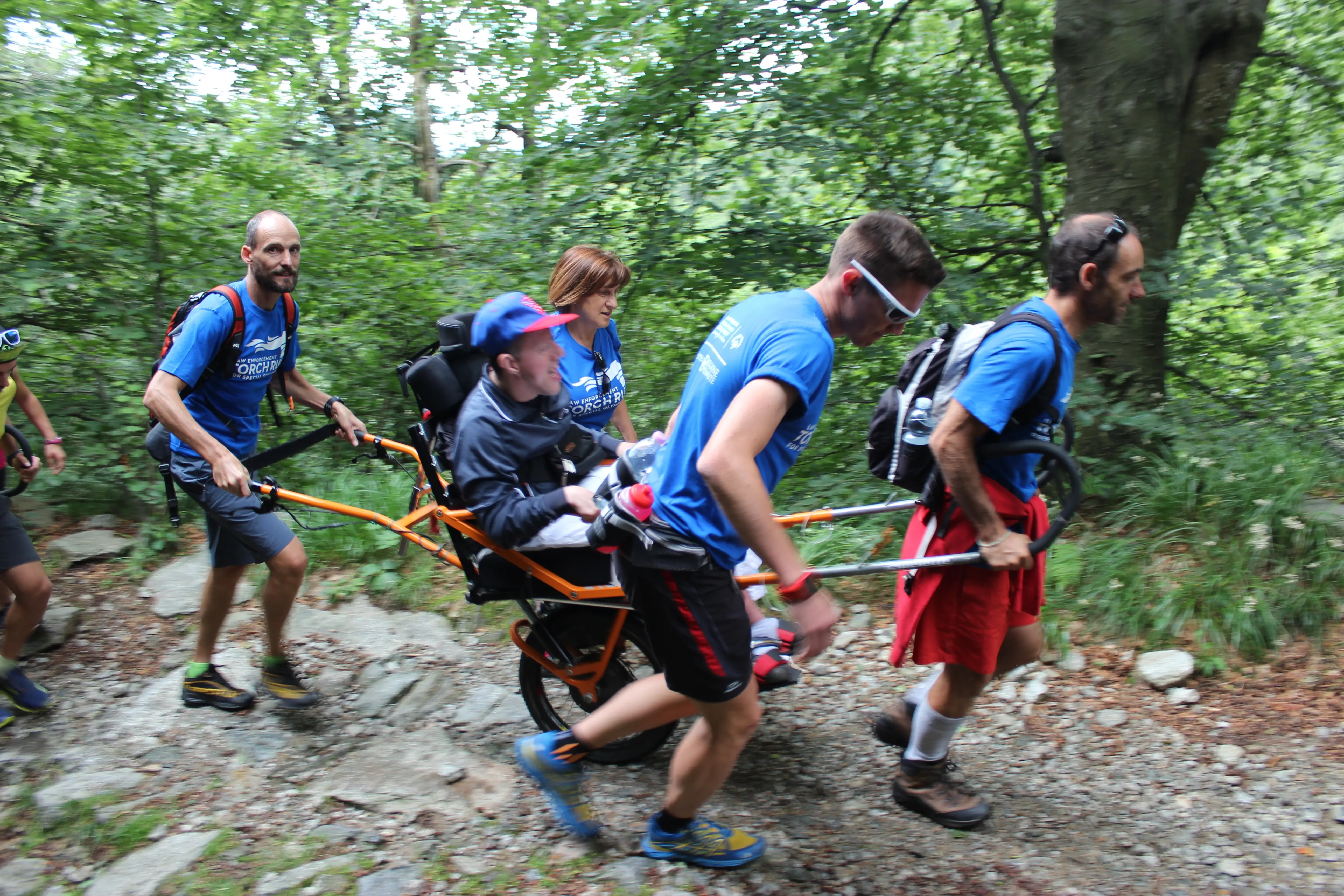 Ragazzo in koelette spinto da giovani lungo un sentiero di montagna
